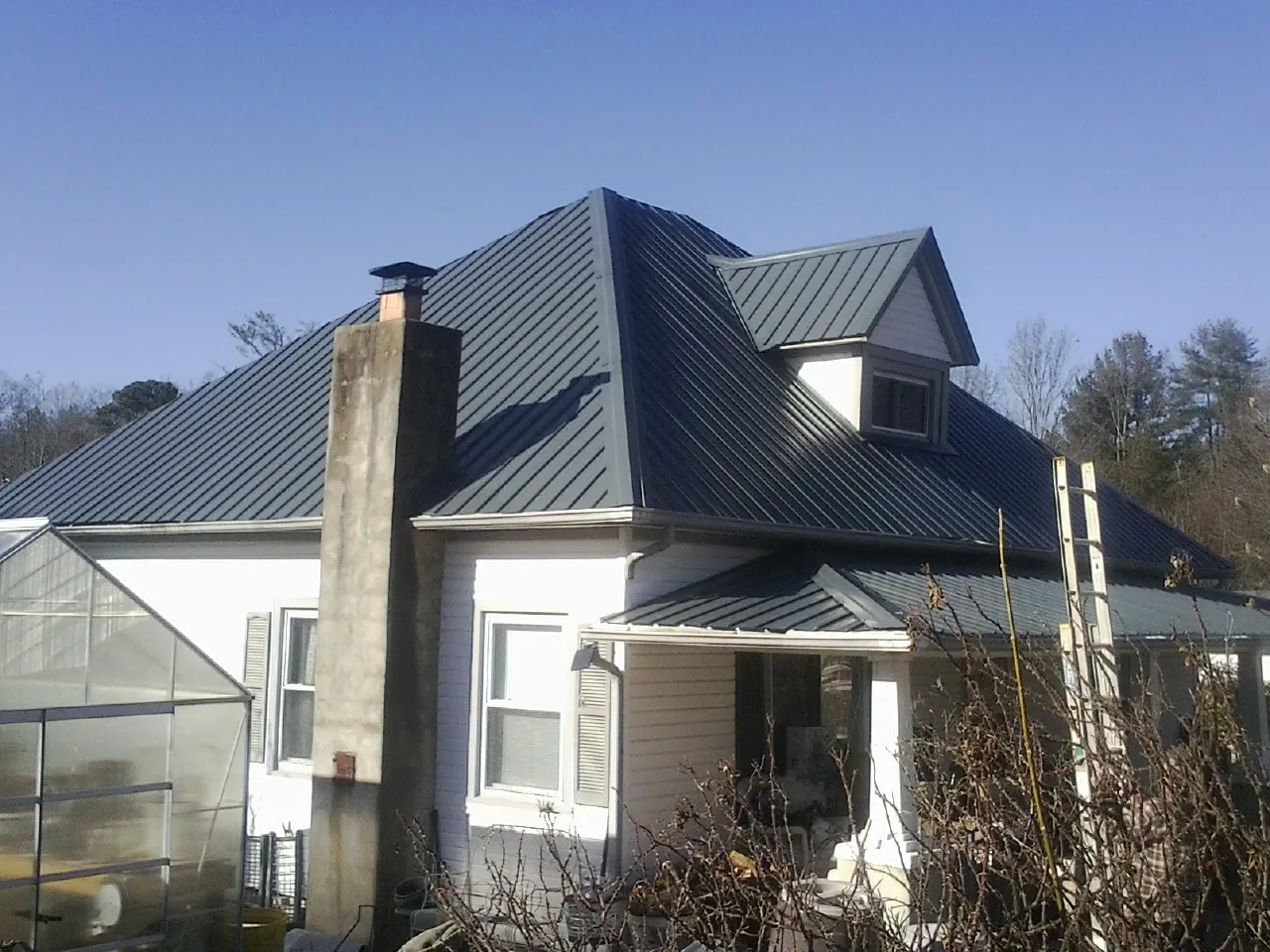 Dark blue standing seam metal roof on a white farmhouse with dormer — Slate & Tile Roof Repair by Roofing Brothers in Selah
