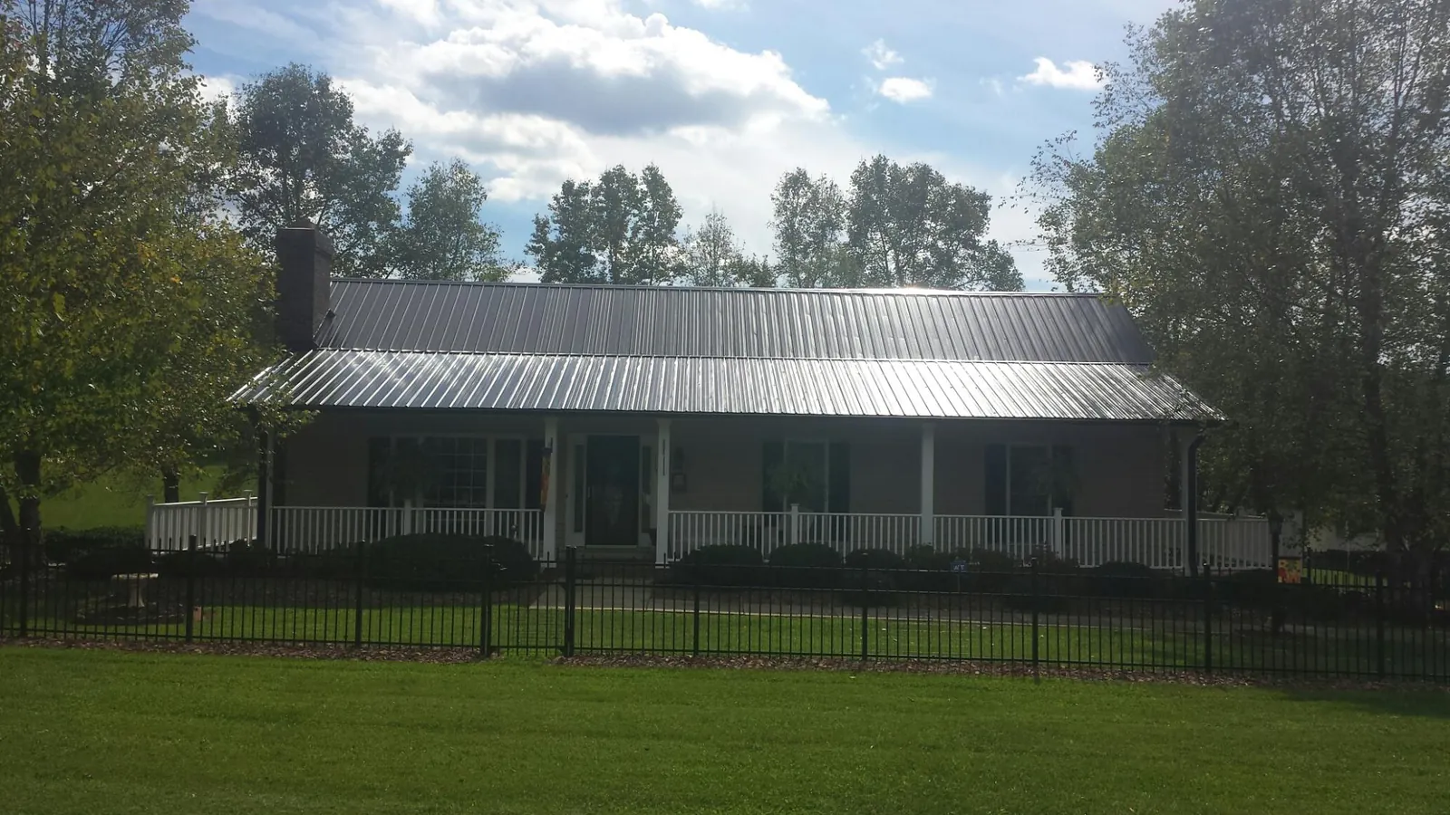 Gray metal roof on a brick ranch with a full width front porch — Gutter Guard Installation work by our crew in Selah