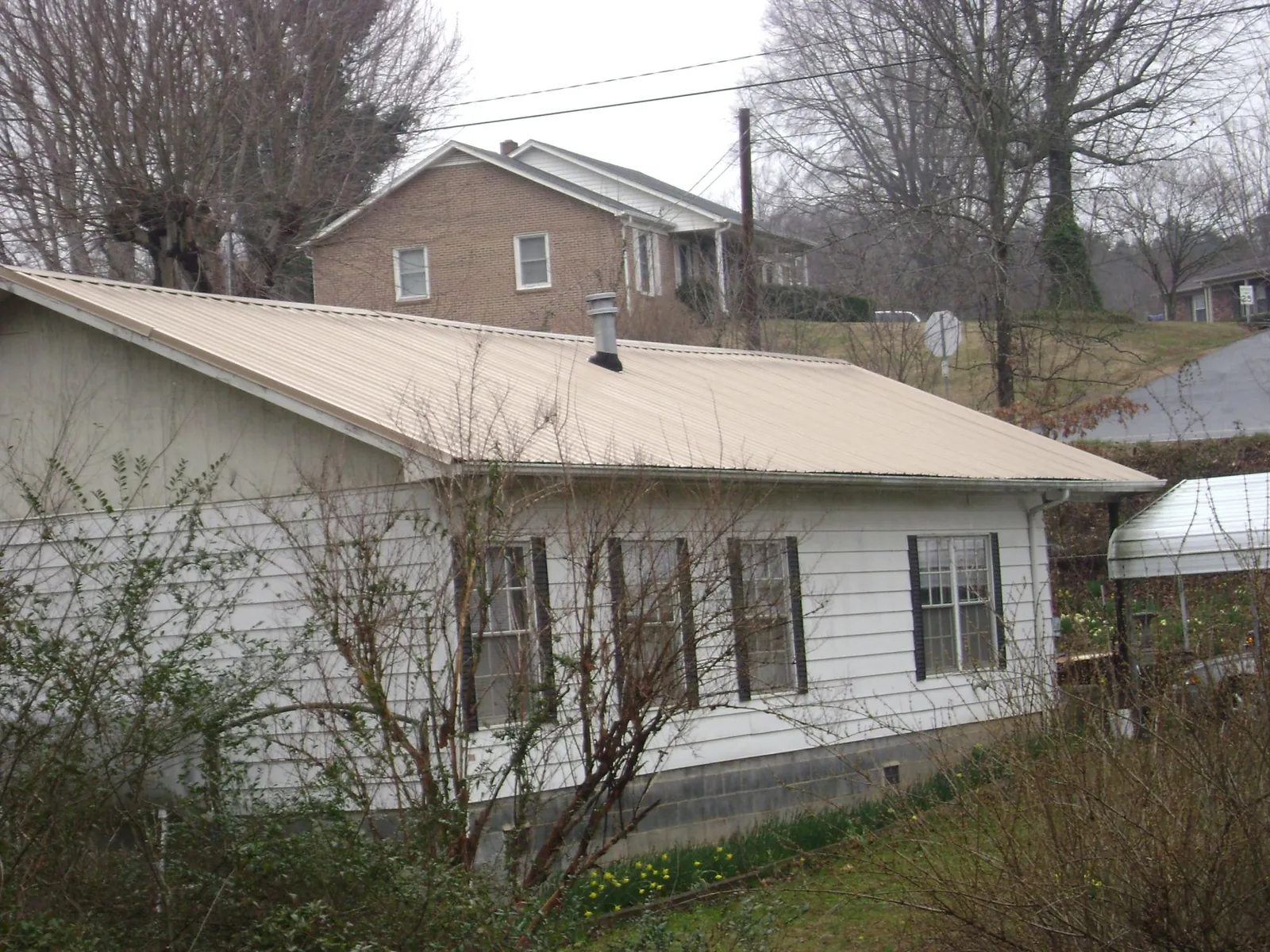 Tan metal roof on a white sided house set into a hillside — Commercial Roofing by Roofing Brothers in Selah