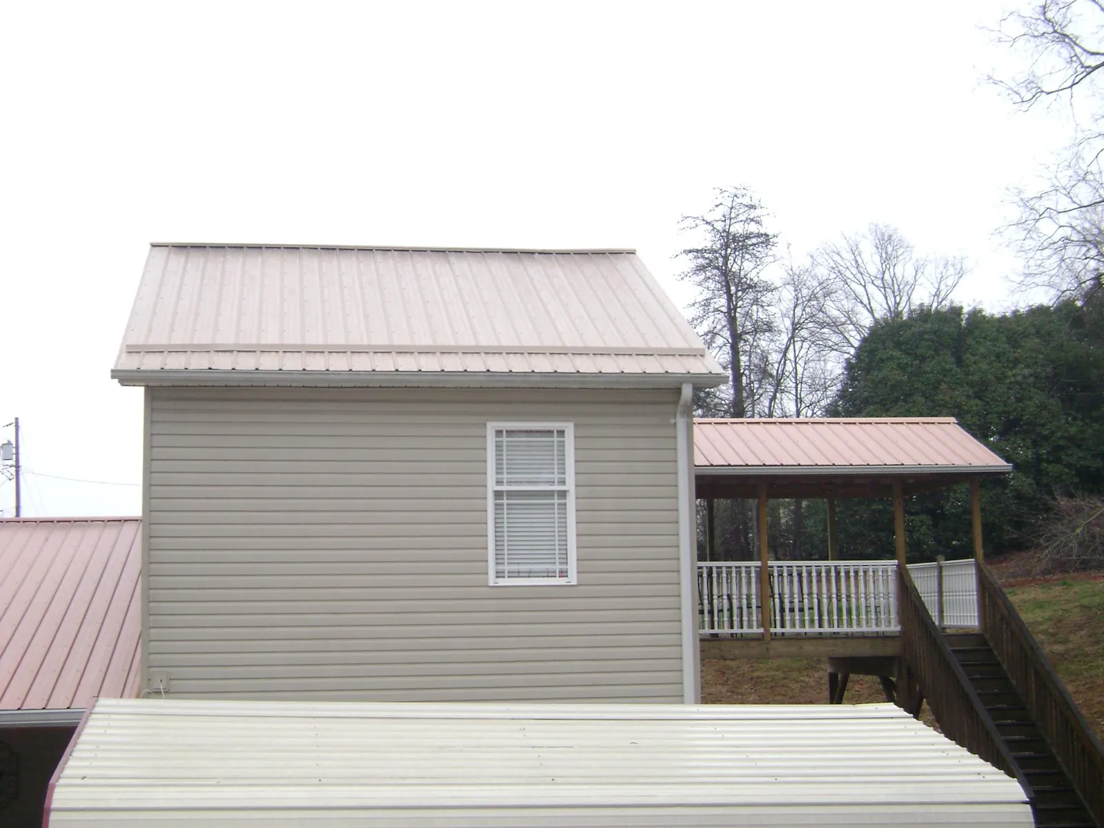 Tan metal roofs on a two story addition and attached porch, from a Roof Replacement job in Selah