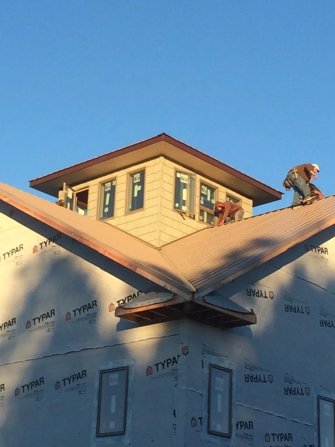 Roofers working around a rooftop cupola on a new metal roof at sunset — Roof Waterproofing in Selah by Roofing Brothers